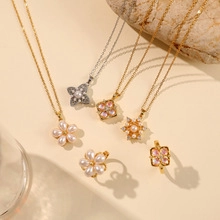 Set di gioielli dorati floreali con collane e orecchini su superficie di marmo beige