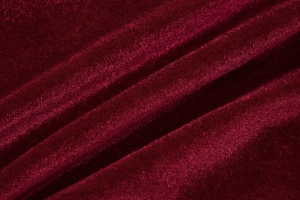 Macro close-up of premium burgundy velvet fabric with elegant folds and silky texture