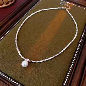 Elegant irregular silver beaded necklace with round lustrous pearl pendant on dark velvet