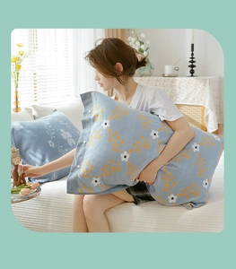 Detail of blue cotton pillowcase with yellow leaf pattern and decorative button closure
