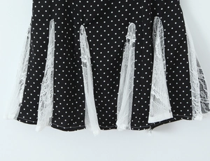 Detailed close-up of the black polka dot skirt with intricate white lace patchwork hem