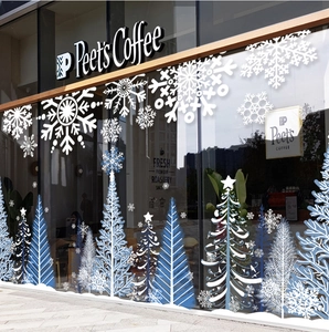 Dettaglio di fiocchi di neve bianchi e alberi di Natale blu su vetrina di una caffetteria