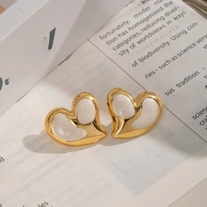 Elegante goldene Herz-Ohrstecker mit weißem Emaille-Inlay auf Vintage-Buchseiten
