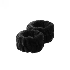 Close-up of a pair of black coral fleece wristbands for washing face to prevent water flow