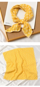 Detail view of cotton linen scarf with yellow geometric grid pattern and white cross design