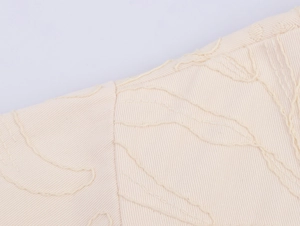 Macro shot of high-density twill fabric and premium 3D embroidery on a beige casual jacket