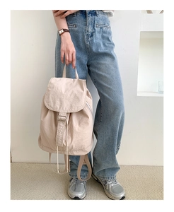 Dettaglio dello zaino beige in nylon con chiusura a coulisse e patta per donne