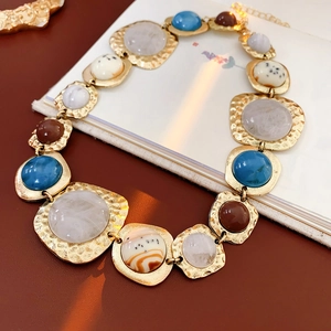 Close-up of vintage golden necklace with hammered texture and colorful gemstones