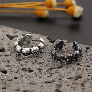 Gothic punk skull rings in silver and gun-black finish on a dark stone background