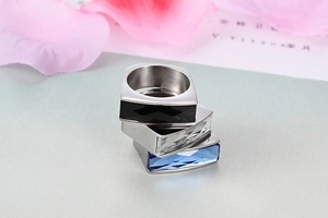 Macro shot of three stacked rings featuring rectangular gems in black, clear and blue