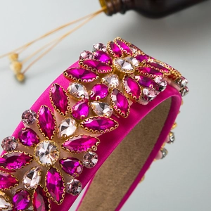Détail du serre-tête en satin rose avec strass colorés et monture dorée