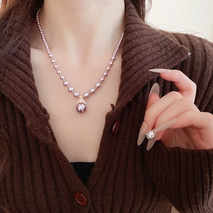 Détail d'un élégant collier de perles mauves et d'une bague assortie avec zircons