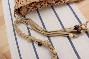 Detail of hand-woven straw bag with bronze metal rings and decorative wooden beads