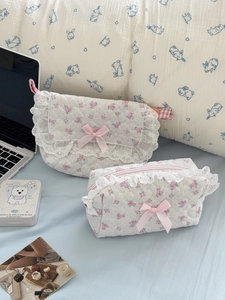 Quilted floral makeup bag set with white lace trim and pink ribbon on blue bedding