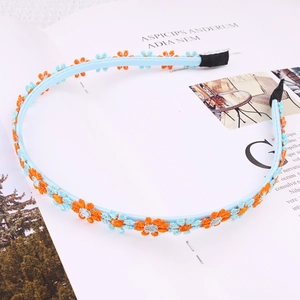 Detail of light blue daisy embroidery on a satin headband with intricate floral texture