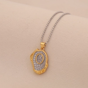 Macro detail of a gold lava textured pendant with sparkling letter O on a silver ball chain