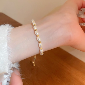 Detail of adjustable pearl bracelet with gold beads worn on wrist with a pull-chain clasp