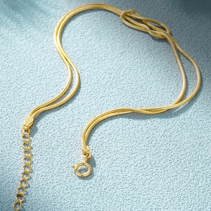 Detail of a golden double-layered snake chain necklace with an adjustable spring clasp