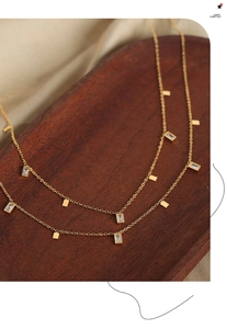 Detailed macro shot of gold square pendants and zircons on a delicate titanium chain