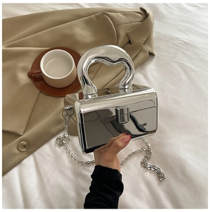 Close-up of silver acrylic box bag featuring unique heart-shaped metal handle and chain