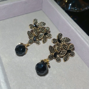 Close-up of vintage gold flower earrings with dark crystals and black bead charms