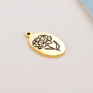 Gros plan du pendentif ovale doré en acier inoxydable avec motif floral de naissance