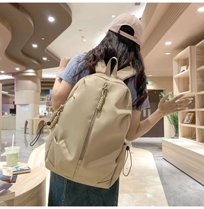 Modern beige large capacity nylon backpack worn by a model in a library setting