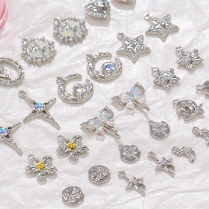 Collection of silver alloy DIY jewelry charms with stars flowers and bows on white fabric