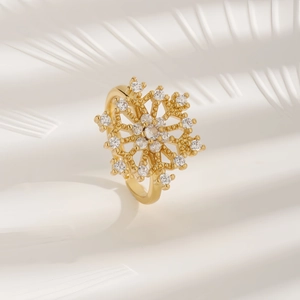 Elegant gold snowflake ring with sparkling crystals on a textured white background