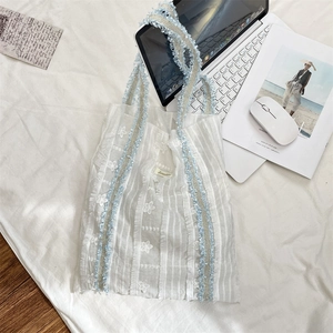 Détail du cabas blanc texturé avec broderie florale et bandoulière tissée bleue