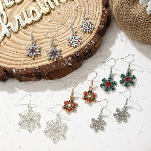 Various Christmas snowflake earrings with rhinestones on rustic wooden and snow background