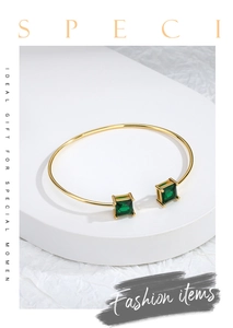 Detailed macro view of the gold open bangle set with two square green gemstones