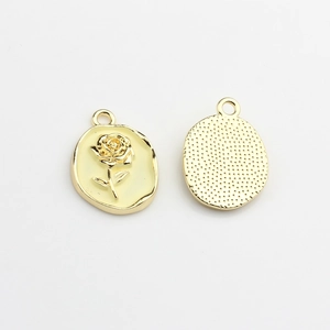 Detailed view of oval enamel rose pendants with textured golden metal backing for DIY jewelry