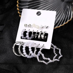 Silver earring set with butterfly and pearl charms on display card in glass tray