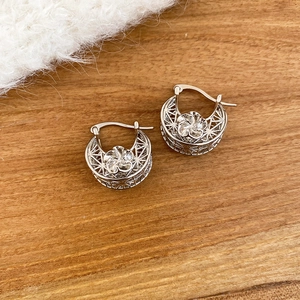 Macro detail of silver hollow flower hoop earrings with intricate geometric mesh patterns