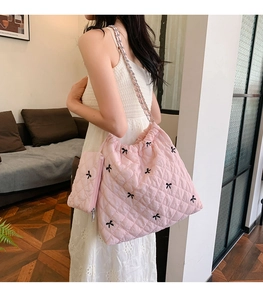 Pink quilted shoulder bag with chain strap and small pouch worn by a model
