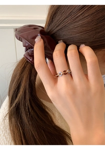 Detail shot of a French vintage ring with gold chain and colored enamel rings on finger