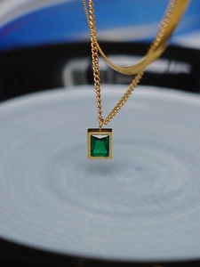 Detail of a double-layered gold snake chain with a vintage emerald green zircon pendant