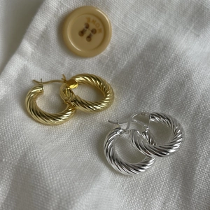 Elegant gold and silver twisted hoop earrings made of 925 sterling silver on linen fabric
