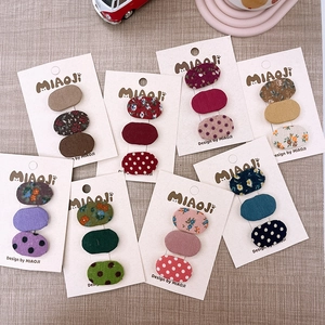 Dettaglio di mini mollette per capelli ovali in tessuto floreale su carta da esposizione