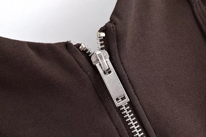 Macro view of dark brown knit fabric texture and polished silver metal zipper detail