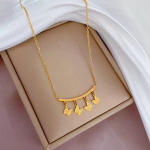 Detail of gold butterfly pendants on a curved bar necklace over white silk background