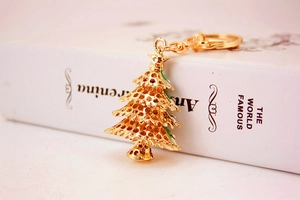 Detailed view of a golden Christmas tree keychain with colorful rhinestones on a white book
