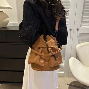 Sac seau en nylon marron avec cordon de serrage porté par un mannequin en intérieur