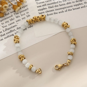 Gros plan d'un bracelet de perles d'opale bohème avec anneaux en acier doré sur fond beige