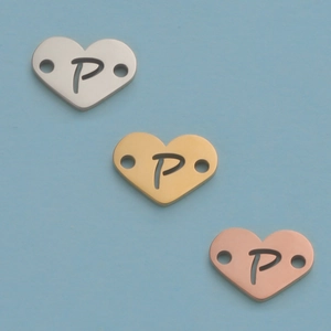Macro shot of 12mm heart shaped pendants in silver gold and rose gold with letter P
