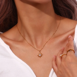 Close-up of gold 18K starburst pendant necklace with a pink zircon stone inlay