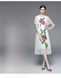 Détails de broderie florale colorée sur robe en tulle blanc avec sequins sophistiqués