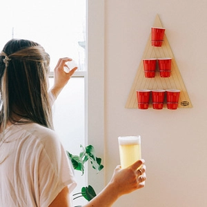 Detailed close-up of a wall-mounted wooden beer pong game with red cups on a triangle board