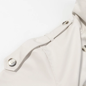 Close-up of the shoulder epaulettes and marble-textured buttons on a beige trench coat